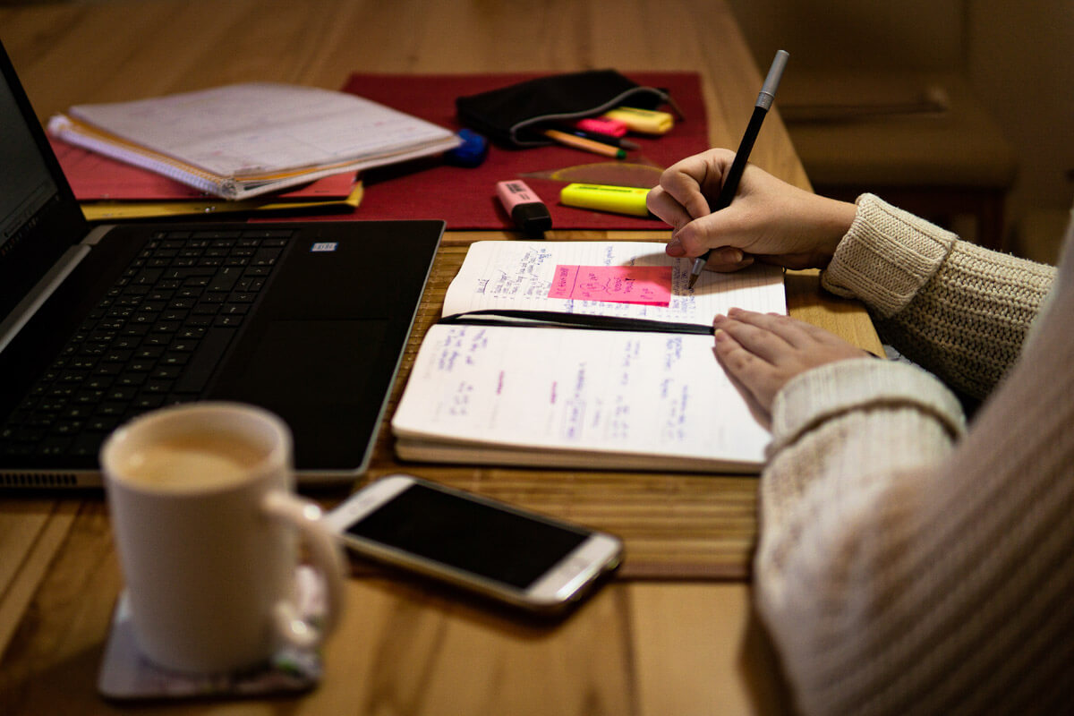 Arbeiten am Laptop mit Notizbuch, Handy und Kaffee
