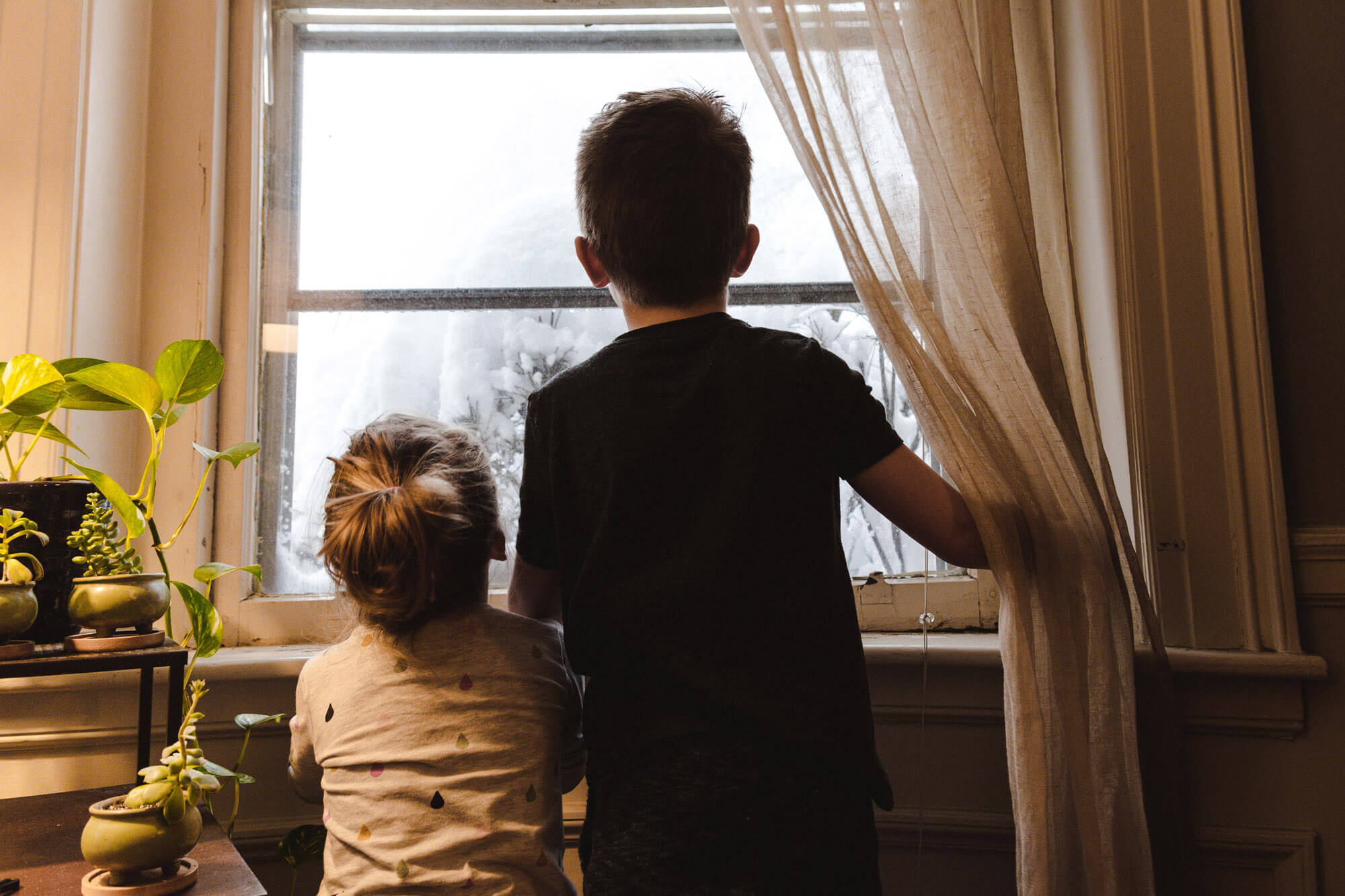 Kinder schauen im Winter aus dem Fenster